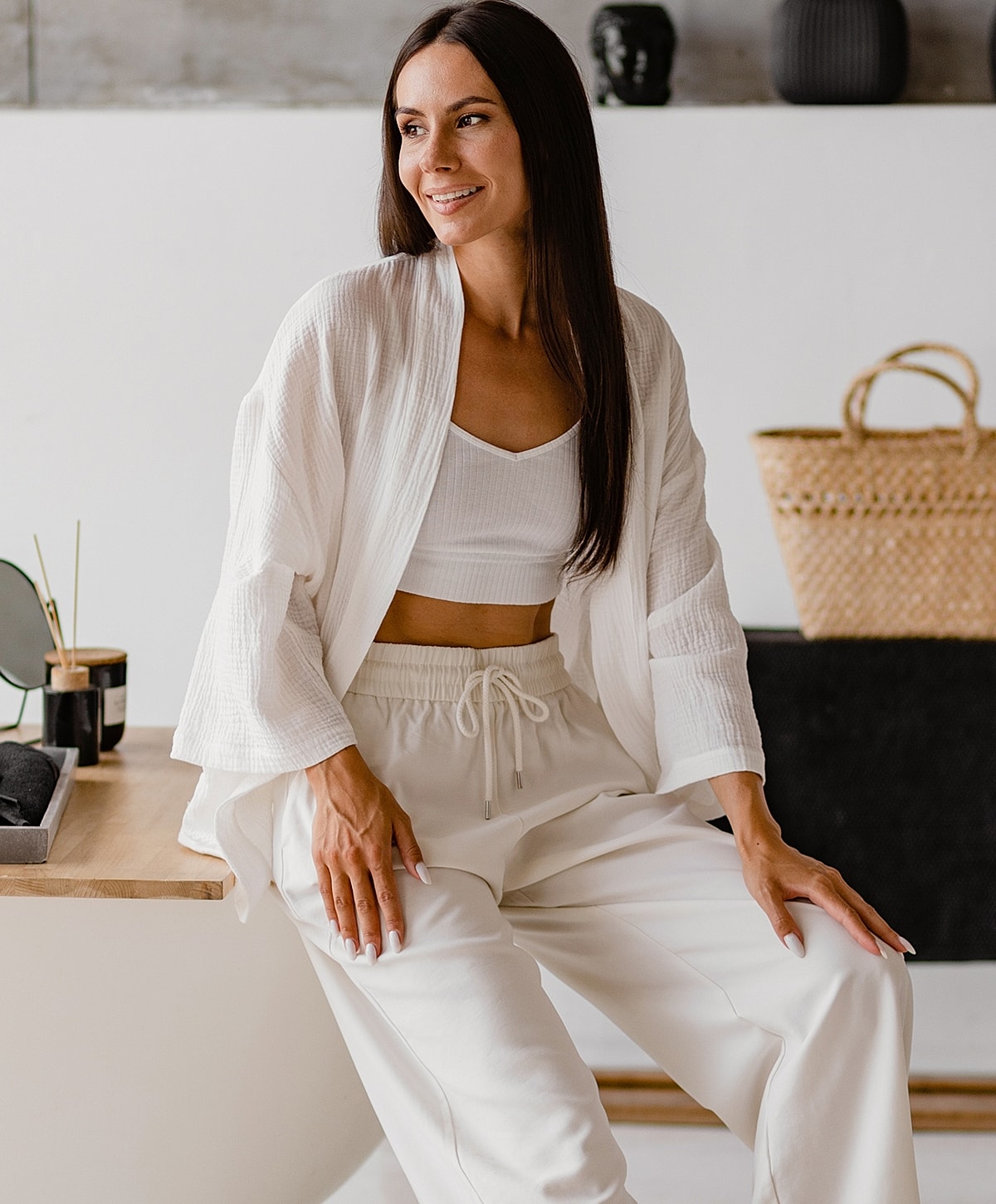 Woman in white outfit, relaxed indoor setting.