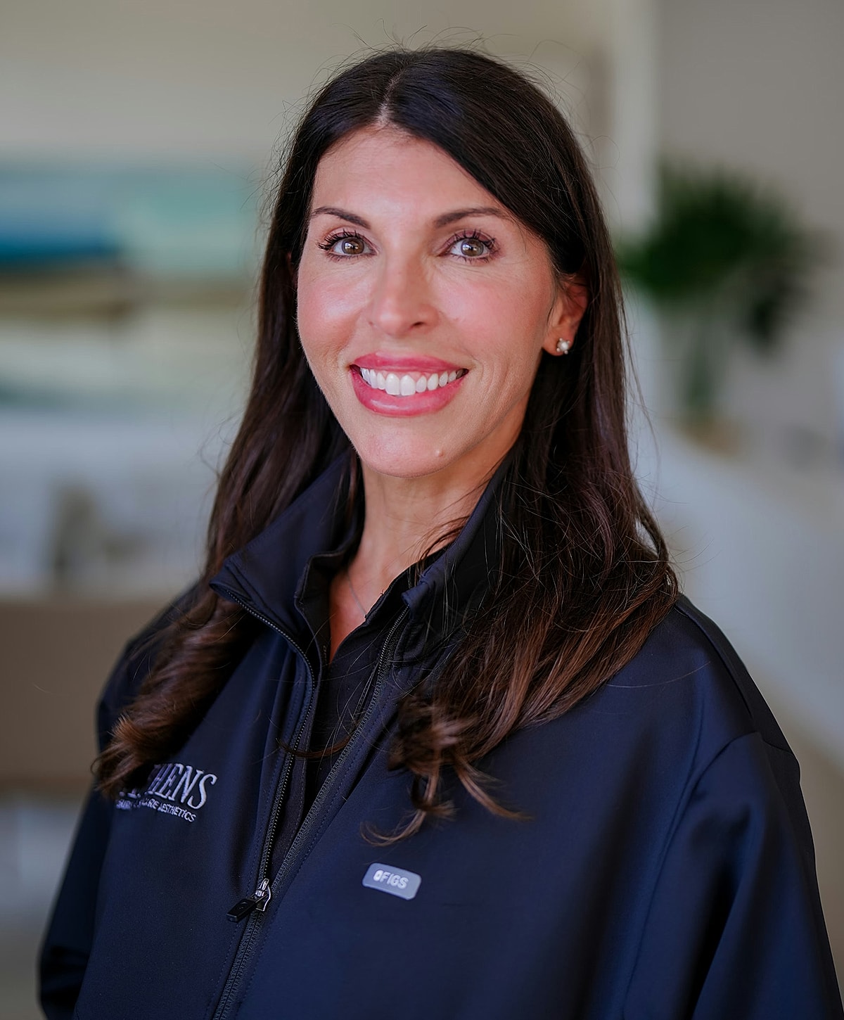 Smiling woman in professional attire, indoor setting.