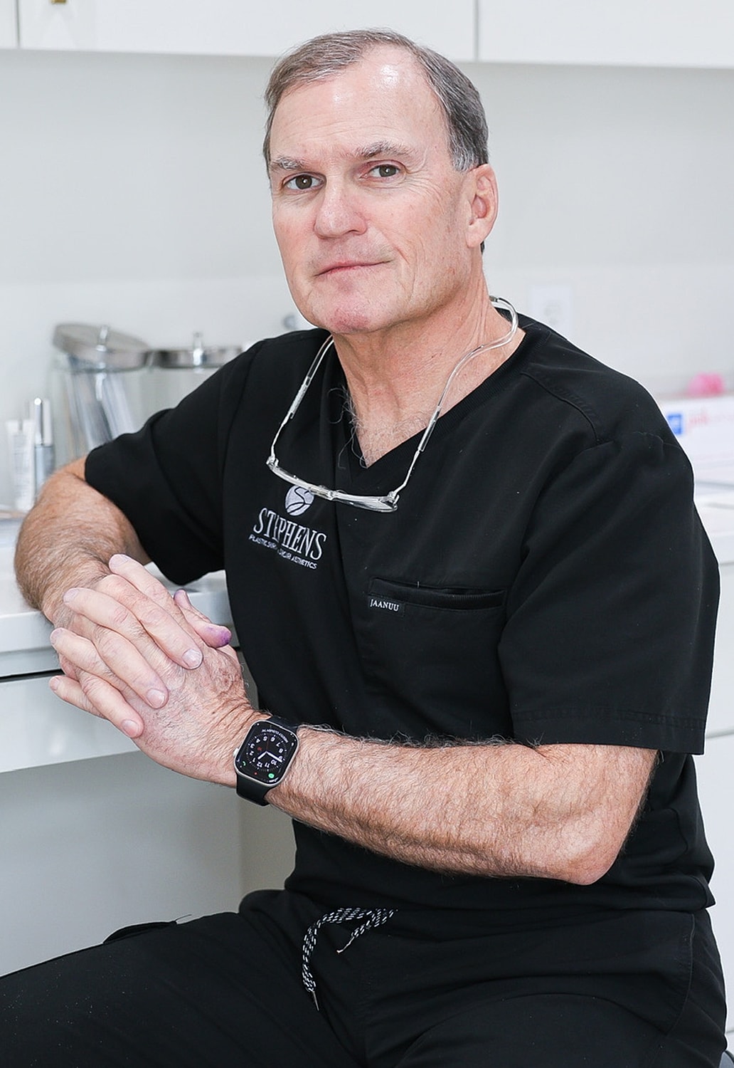 Doctor seated in a medical office, hands clasped.