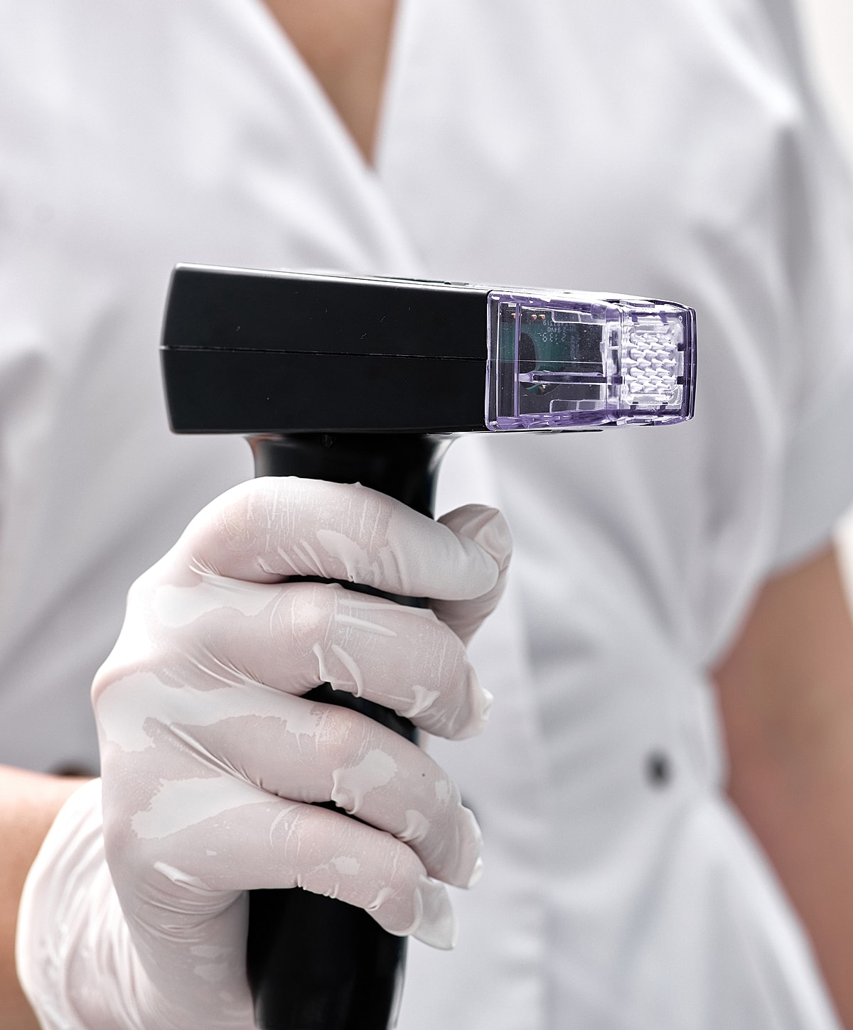 Hand holding a medical device for skin treatment.