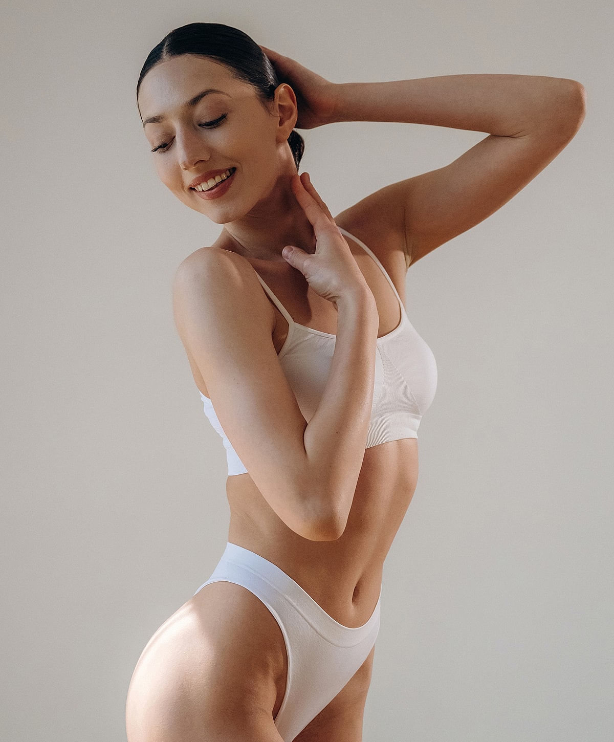 Model posing in white activewear, smiling.