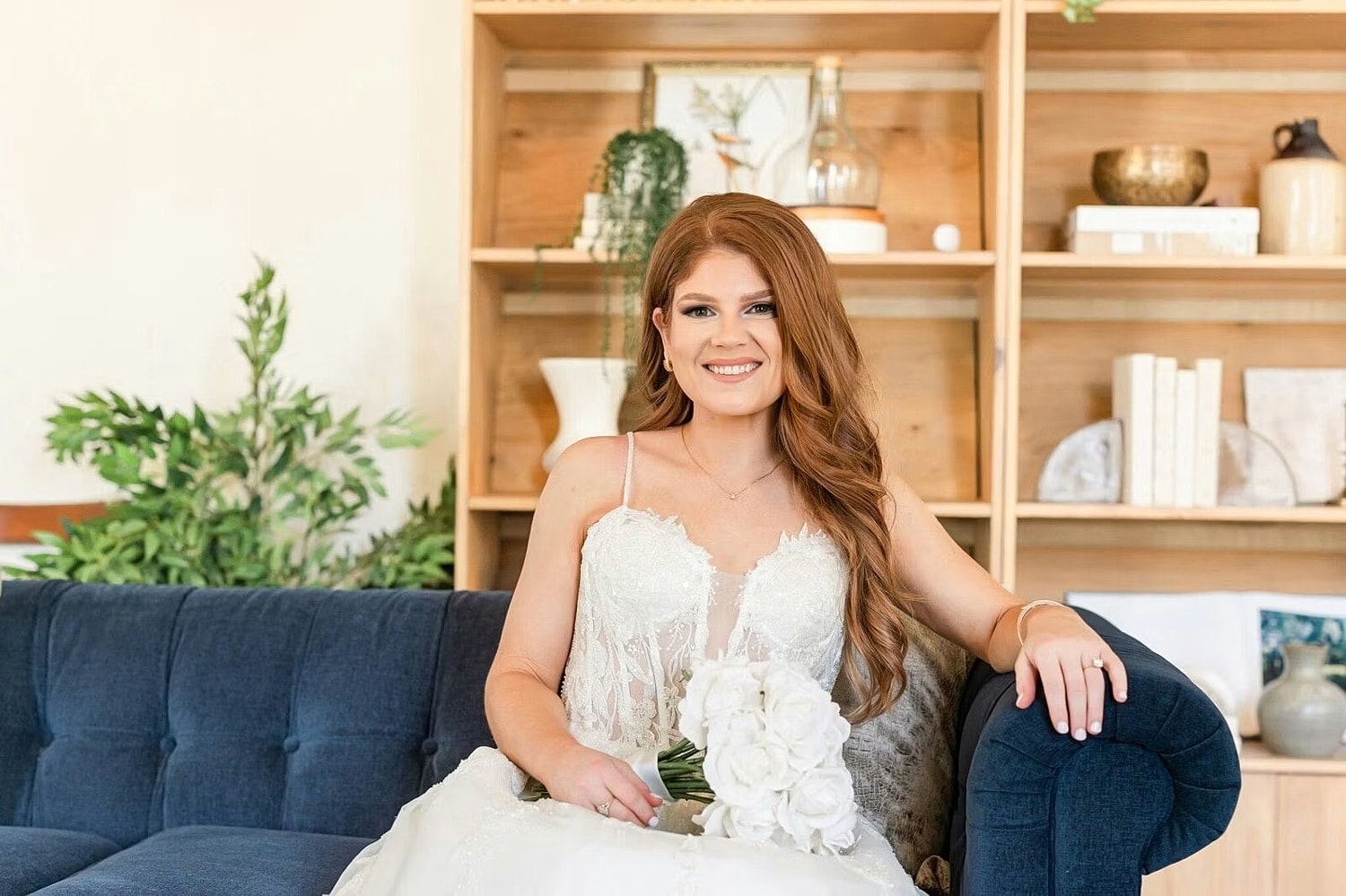 Bride sitting on a sofa with bouquet.