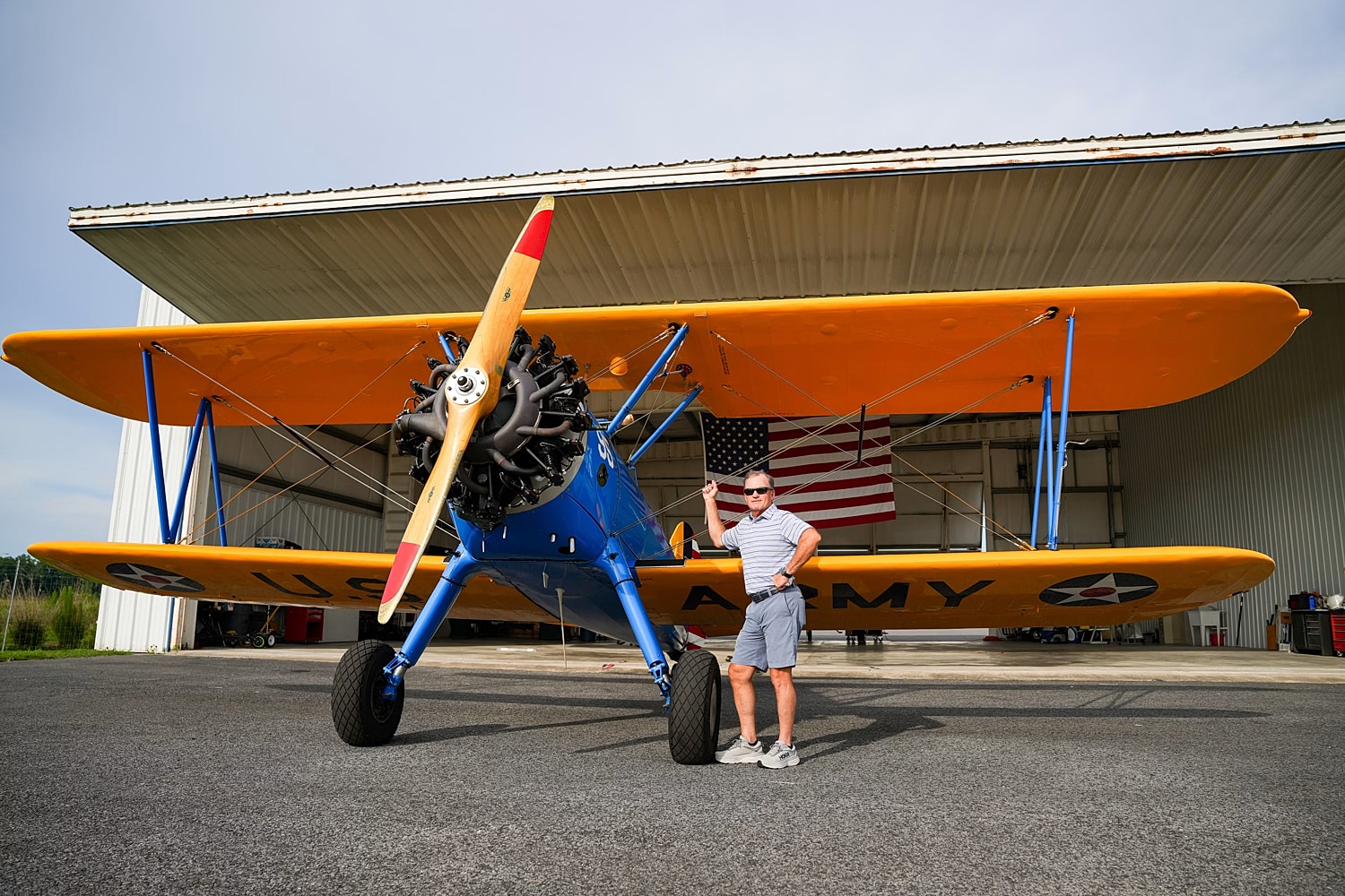 Man posing beside vintage military aircraft.