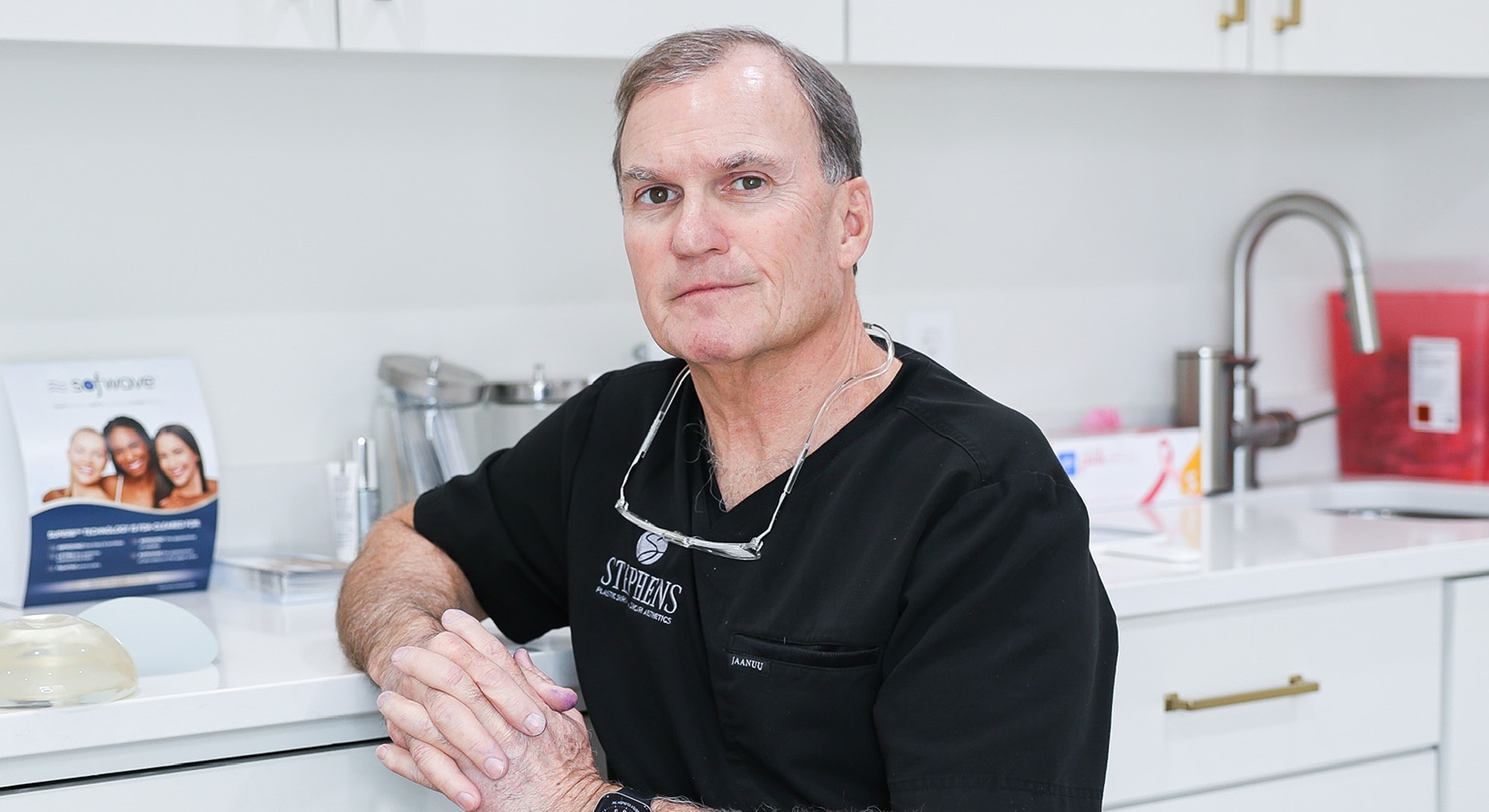 Doctor in a medical office, hands folded.